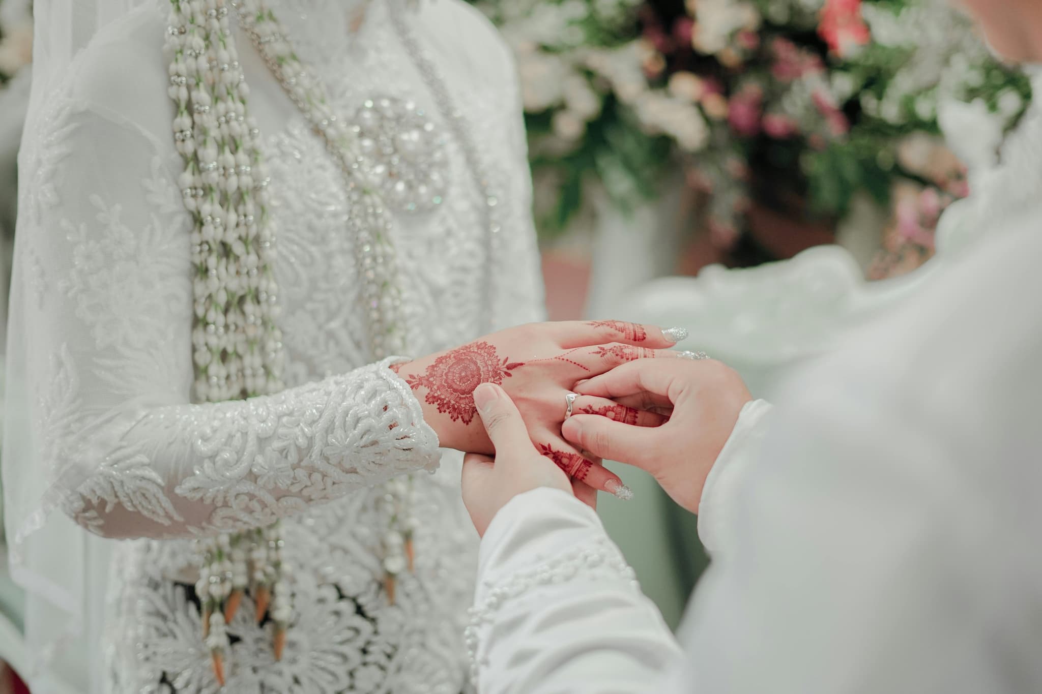 A ring being placed on a bride's henna-decorated hand